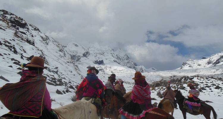 Groep mensen te paard in besneeuwde bergen.