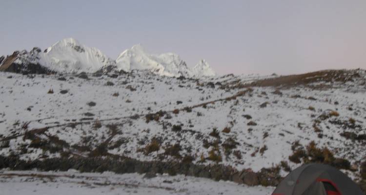 Een besneeuwd landschap met verre bergen en een tent.