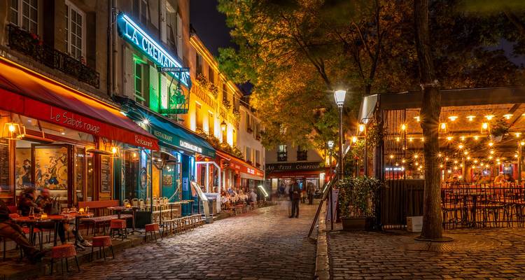 Scène nocturne d'une rue parisienne animée avec des cafés.