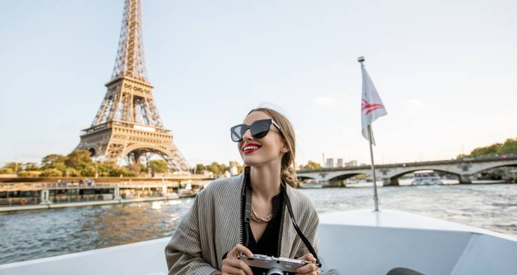 Femme souriante sur un bateau avec la Tour Eiffel en arrière-plan.