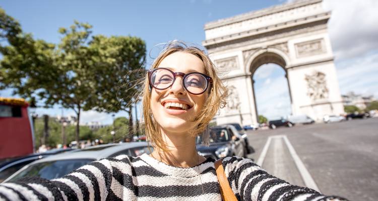 Gros plan d'une femme posant devant l'Arc de Triomphe.