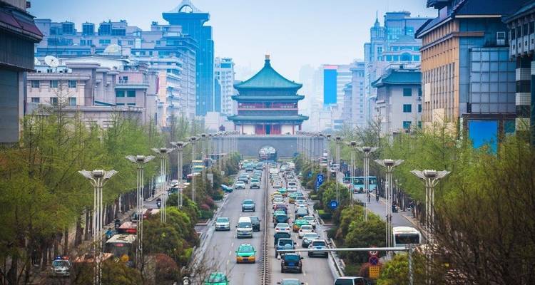 Street view with a pagoda in the background and vehicles on a busy road.