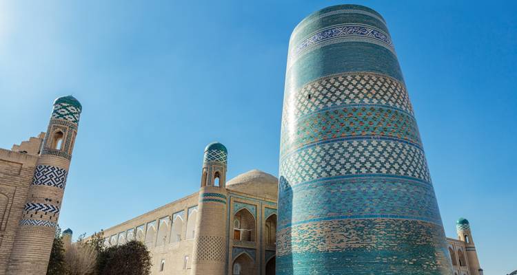 Un grand minaret dans un complexe historique avec maçonnerie de briques et décoration en carrelage.