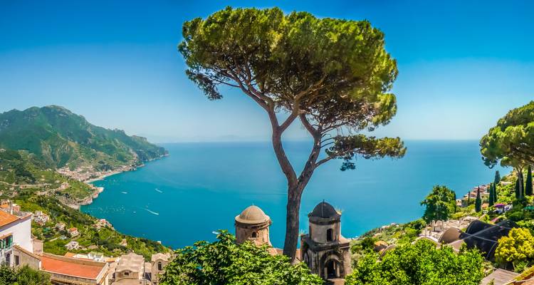 Vista panorámica de Ravello con árboles y mar lejano.