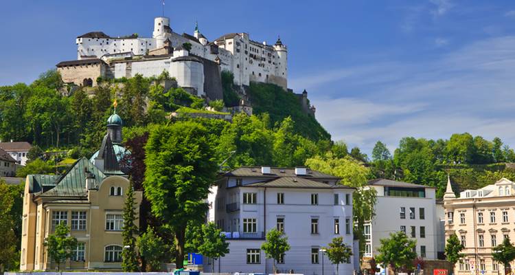 La Fortaleza de Hohensalzburg de Salzburgo se alza sobre los techos frondosos y las agujas de la ciudad contra un cielo azul brillante.