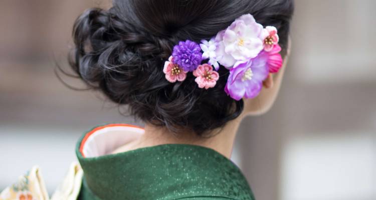 Close-up of the back of a woman's head with a floral arrangement in her hair, wearing traditional clothing.