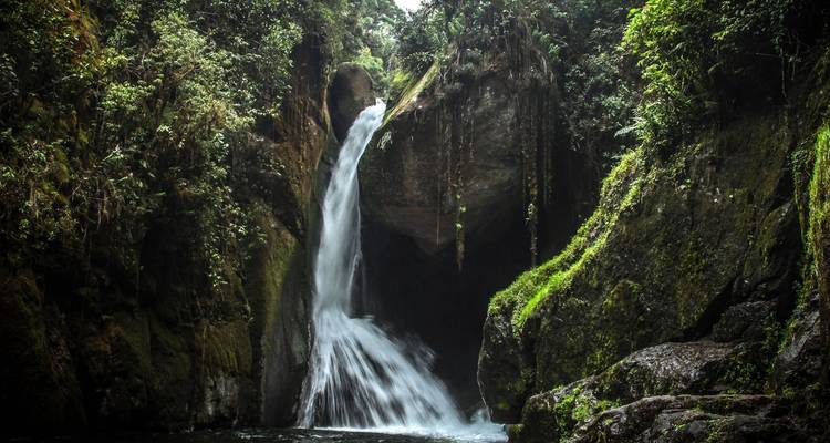 Dramatic waterfall cascading down a rocky cliff surrounded by greenery.
