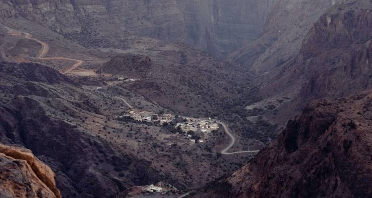 Vista aérea de un valle montañoso escarpado con un pequeño pueblo enclavado en su interior.