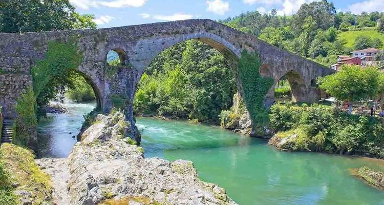 A historic stone bridge over a serene river.