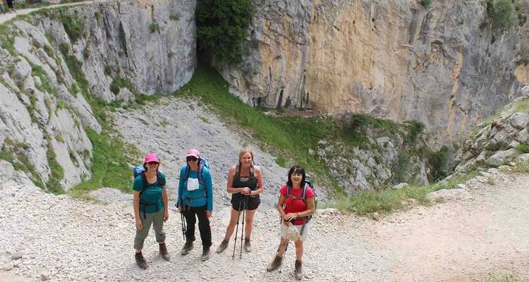 Four hikers standing near a rocky cliff.
