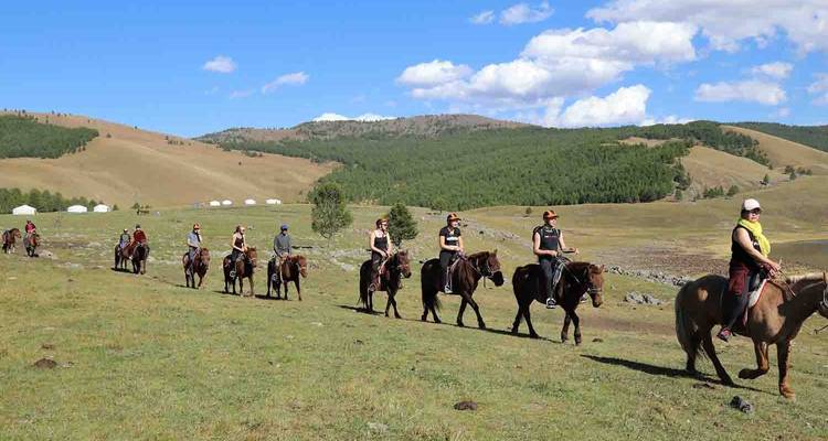 Gente montando caballos en fila a través de vastas llanuras.