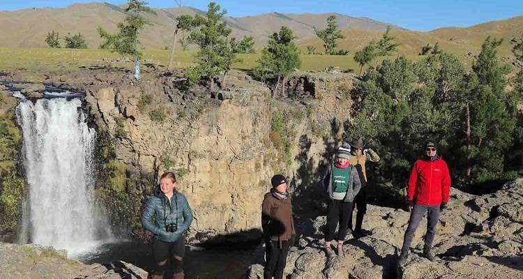 Grupo de personas cerca de una cascada y árboles.