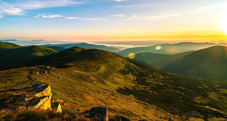 Vast mountain range bathed in golden sunlight at sunrise.