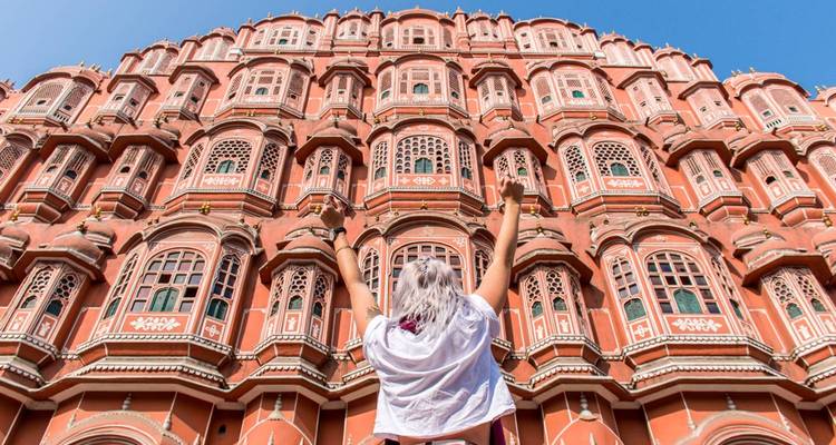 La façade du Hawa Mahal avec une personne qui célèbre devant.