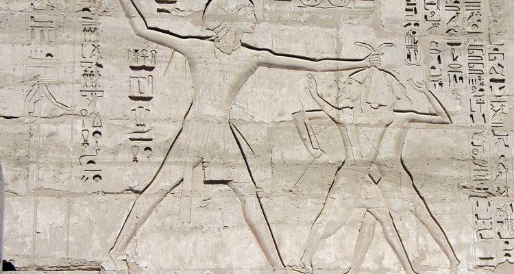 Nahaufnahme von antiken Schnitzereien, die Figuren auf einer Steinwand darstellen.