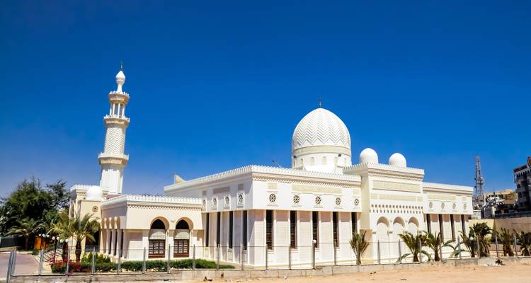 Elegante mezquita blanca con cúpulas y minarete contra un cielo azul profundo en Aqaba.