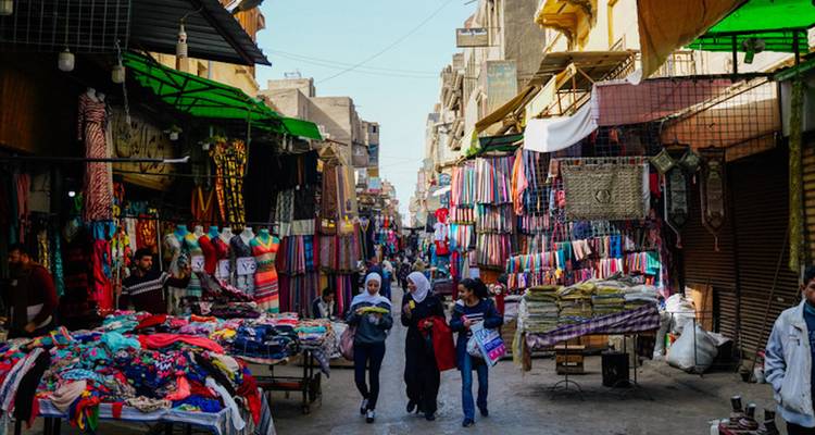 Bunte Marktstrasse in Kairo mit Einheimischen, die zwischen Textilien und Souvenirs einkaufen.