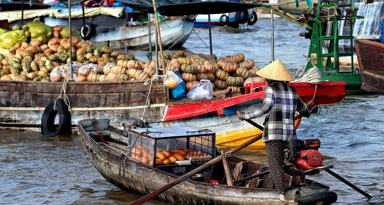Floating market with various boats selling goods and a person rowing.