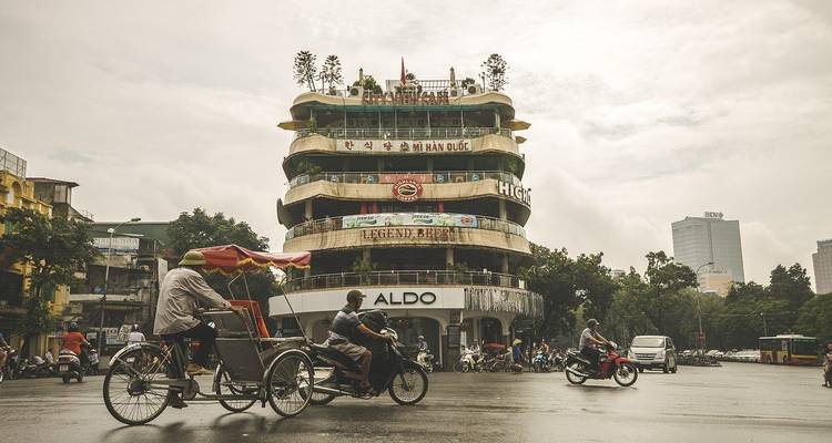 City street with bicycles, distinct architecture, and a round building in Hanoi.
