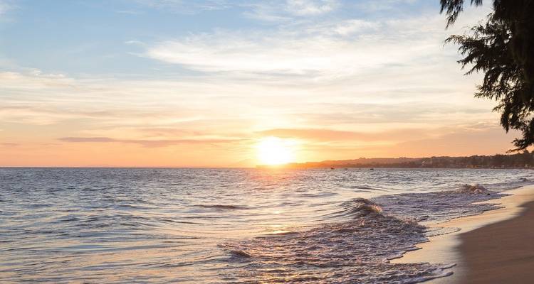 Beautiful sunset over a tranquil ocean with gently lapping waves.