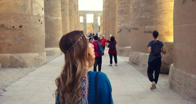 Touristen, die durch große altägyptische Säulen gehen