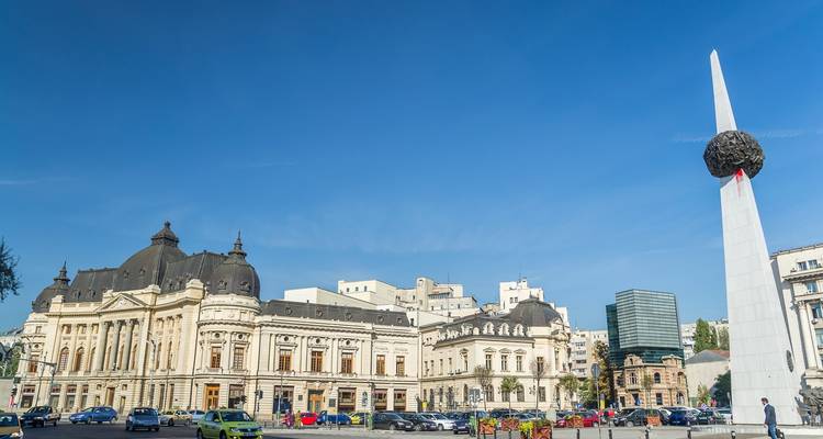 Plaza de la ciudad con edificios históricos y un monumento moderno.