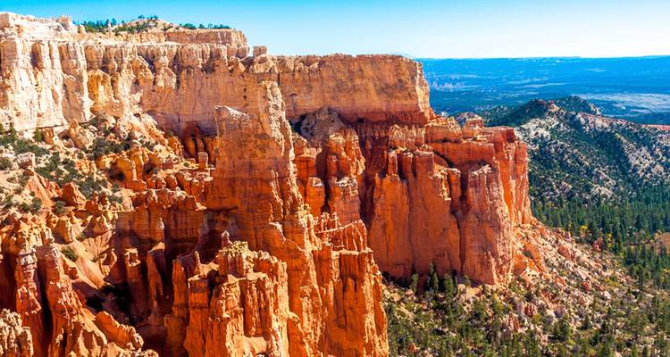 Los impresionantes hoodoos de color naranja brillante se alzan en medio de una vista panorámica de cañón