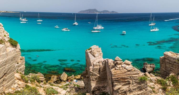 Ein wunderschöner Küstenblick mit türkisfarbenem Wasser und Segelbooten an einem sonnigen Tag.
