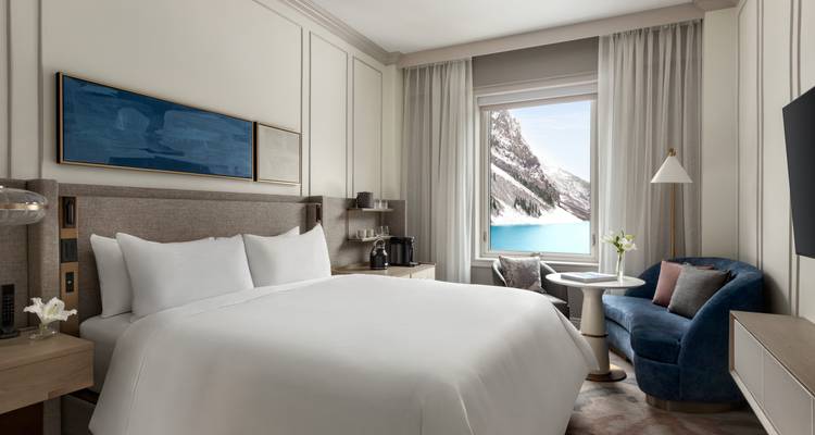 Chambre d'hôtel élégante avec vue sur les eaux turquoise du lac Louise et les falaises spectaculaires.