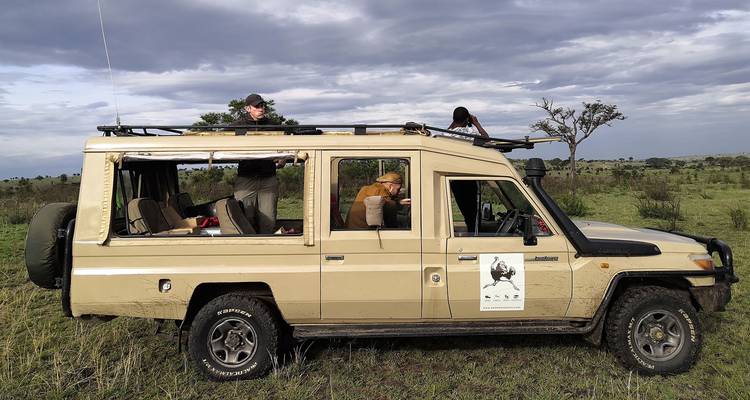 Toeristen in een safarivoertuig op een game drive in een savanne.