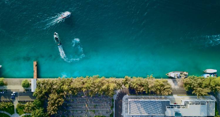 Vista aérea de embarcaciones en agua azul turquesa con una línea costera.