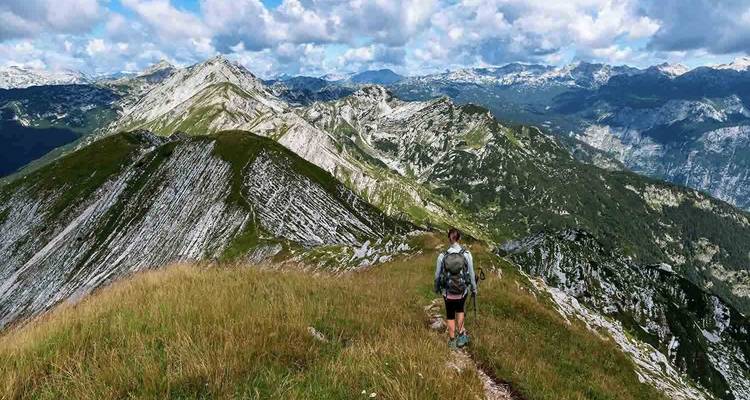 Randonneur marchant le long d'un sentier de montagne avec des vues panoramiques.