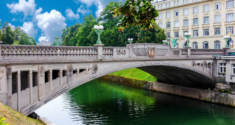Pont élégant enjambant un canal avec des bâtiments historiques en arrière-plan.