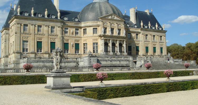 Baroque Château de Vaux-le-Vicomte with manicured gardens and classical statues under blue skies.
