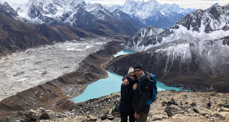 Ein Paar posiert vor einem Bergsee und schneebedeckten Gipfeln.