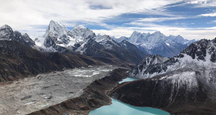 Ein Bergsee umgeben von hoch aufragenden schneebedeckten Gipfeln.