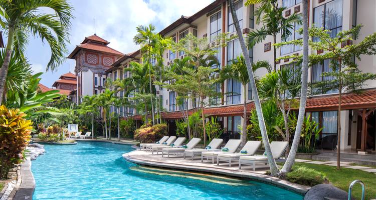 Hôtel entouré de plantes tropicales et d'une piscine scintillante.