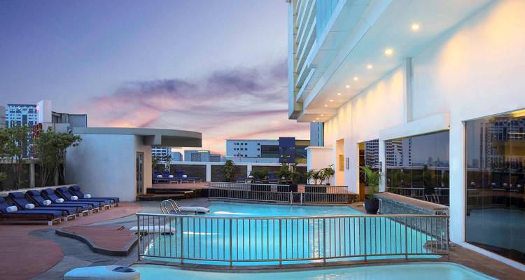 Une piscine sur le toit d'un bâtiment d'hôtel moderne au coucher du soleil.