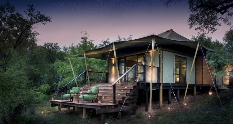 Luxuriöses Safari-Zelt mit Terrasse, umgeben von Waldbäumen.