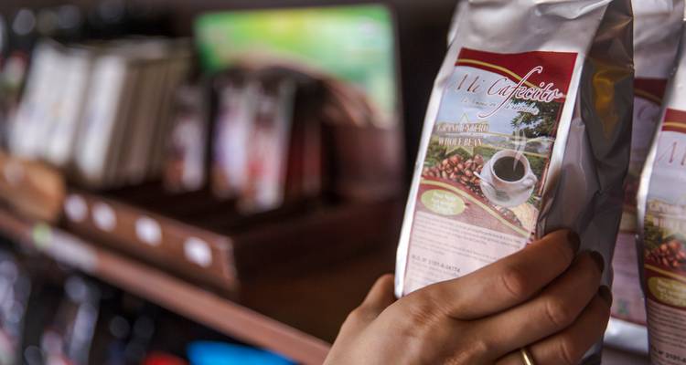El cliente sostiene una bolsa plateada de café empaquetado localmente en una tienda.