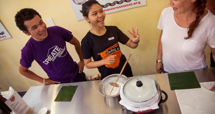 Los participantes se ríen durante una clase de cocina práctica, removiendo masa y compartiendo consejos.