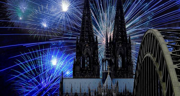 Kölner Dom Türme und Hohenzollernbrücke silhouettiert vor farbenfroher Feuerwerksshow