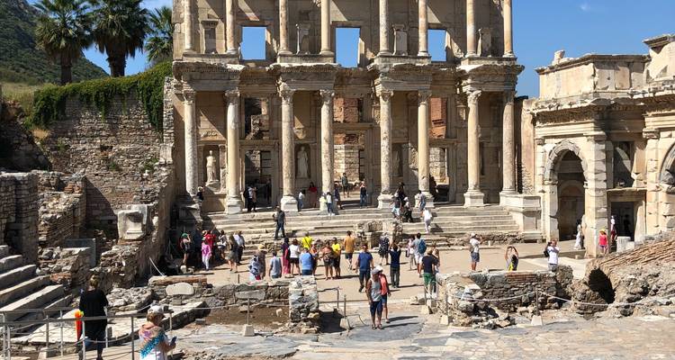 Ruinas de una biblioteca antigua con muchos turistas explorando.