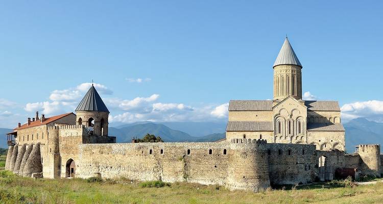 Iconische stenen kerk met een vestingmuur in een landelijke omgeving.
