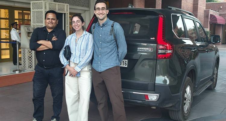 Group of people posing with a car in a driveway.