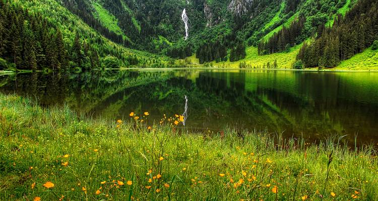 Lush green valley with a lake and waterfall.