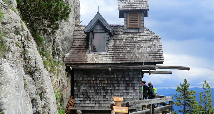 Une hutte construite dans le flanc d'une montagne avec des gens à proximité.
