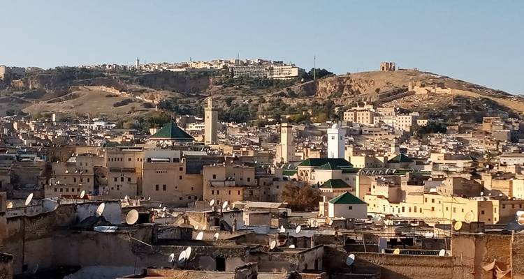 Panoramablick auf die Stadt mit Hügeln im Hintergrund.