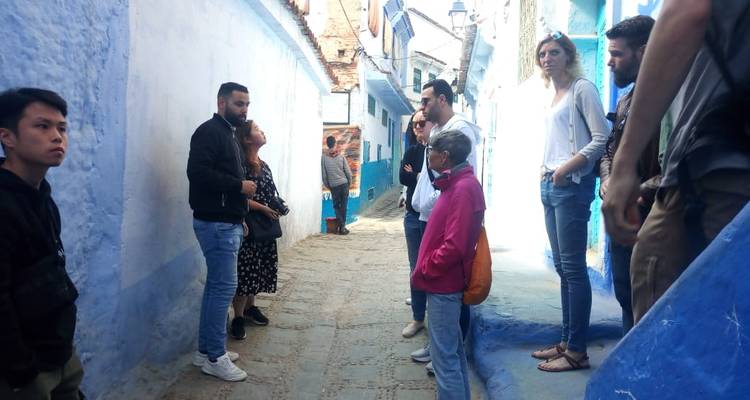 Touristen in einer engen Straße mit blau gestrichenen Wänden.