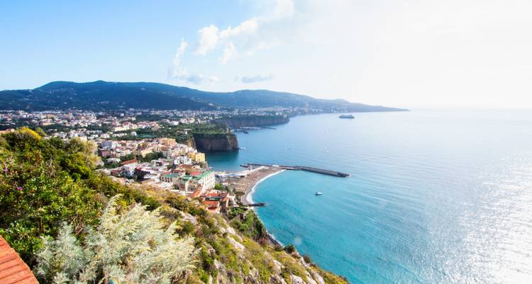 Vista de un pueblo costero desde un punto elevado con playas y mar azul.